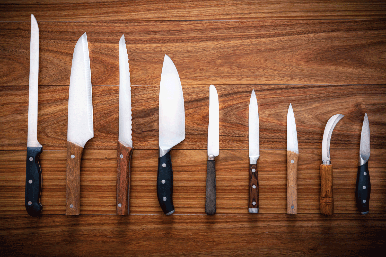 Kitchen knifes inventory on wooden background in a row arrangement
