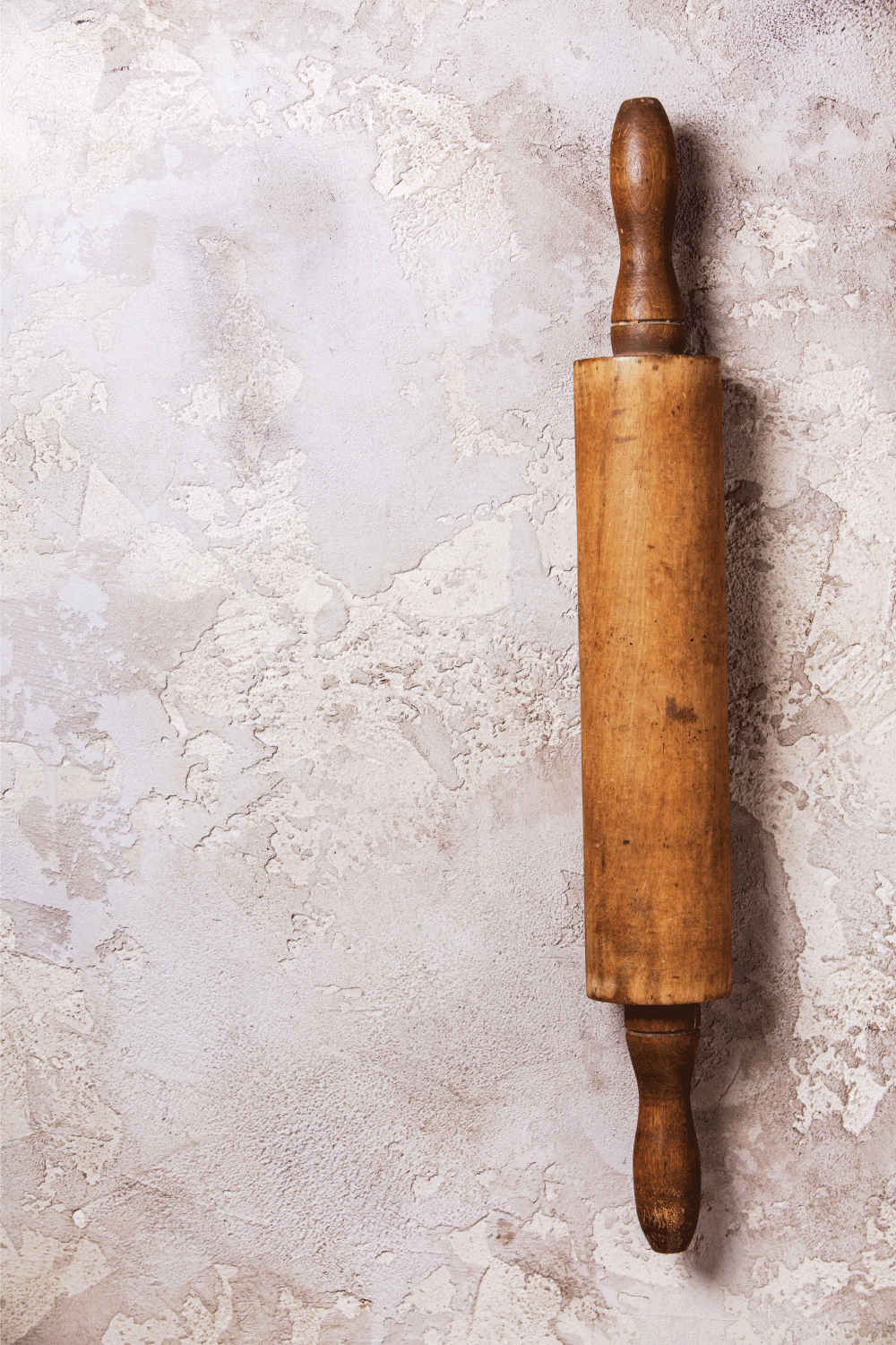 Old wooden rolling pin on rustic stone background