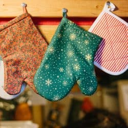 Oven mittens potholders hang in kitchen against the background of blurry kitchen appliances, Are Oven Mitts Heat Resistant?
