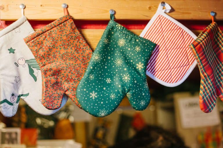 Oven mittens potholders hang in kitchen against the background of blurry kitchen appliances, Are Oven Mitts Heat Resistant?
