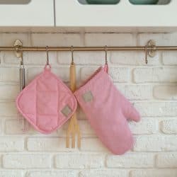 Pink colored oven mitts hanged on the kitchen wall, Where Do You Store Oven Mitts?