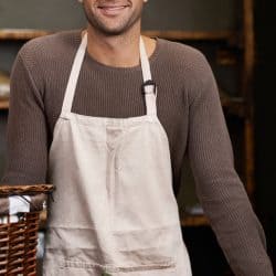 Portrait of a handsome young man standing at his food stall with a box of ingredients, Should An Apron Be Lined? [What You Need To Know]