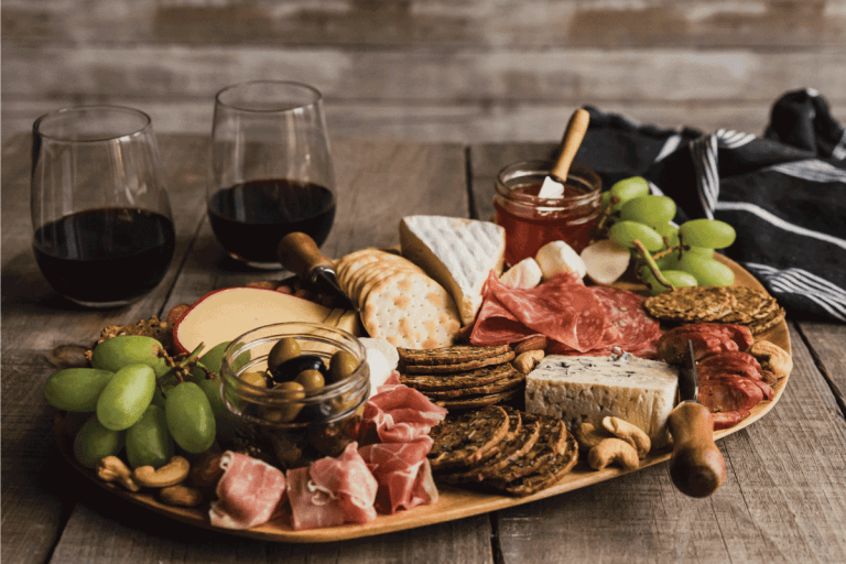 charcuterie board and glasses of wine on wooden table. How Big Should A Charcuterie Board Be
