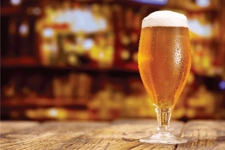 glass of beer bubbling on top of bar. Are Beer Glasses Dishwasher Safe [And How To Wash Them]