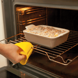 silicone glove for kitchen, woman pulling out casserole from oven using silicone mitts. Are Silicone Oven Mitts Better
