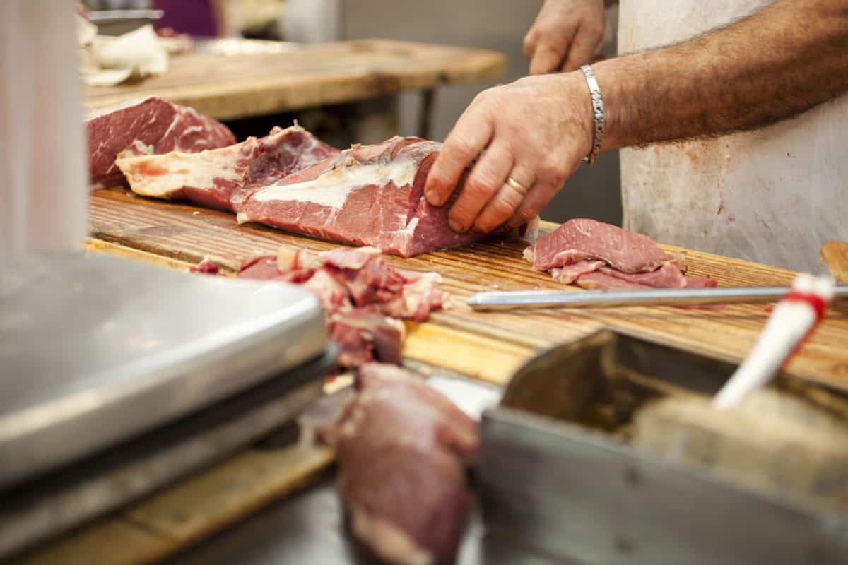 A butcher cutting meat on top of his butcher block
