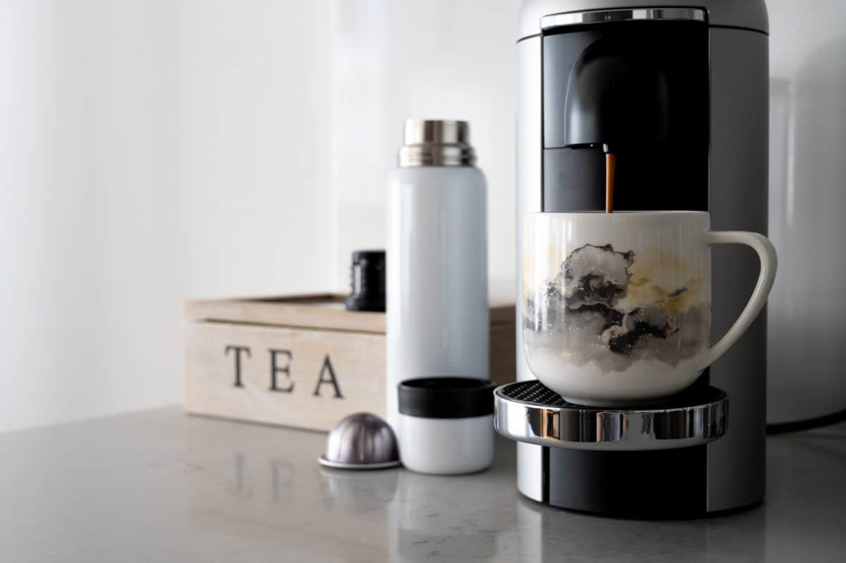 A coffee machine pours hot coffee into a porcelain cup on a kitchen counter perfect for break concept with copy space