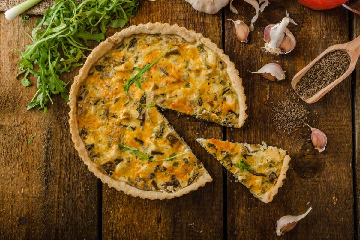 A huge slice of quiche on top of a wooden table