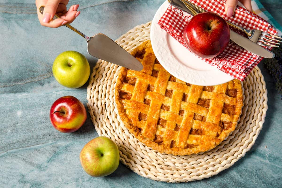 A woman slicing a small piece of apple pie 