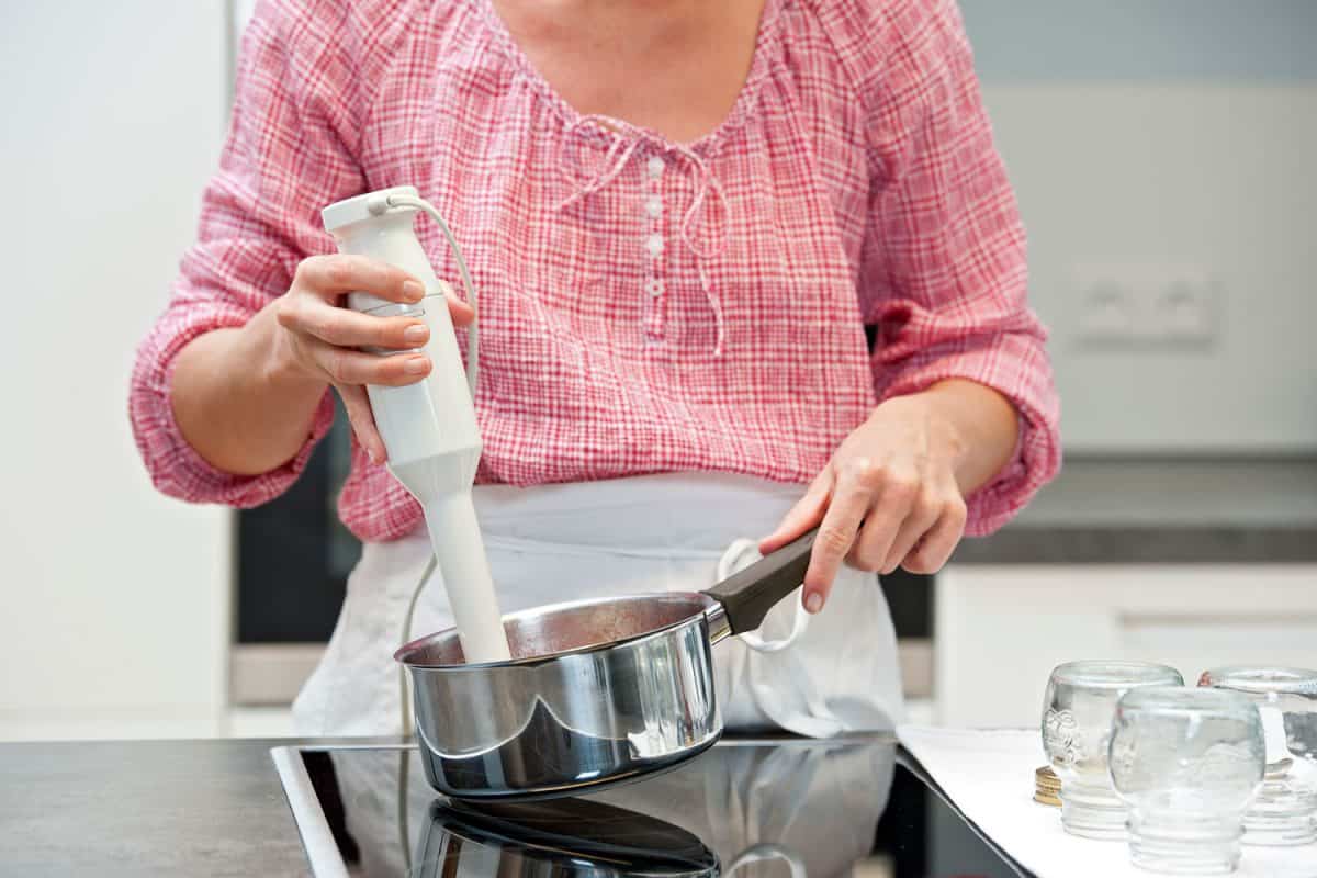 A woman using an immersion blender on her cooking