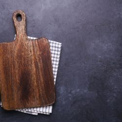 A wooden cutting board with a cloth under it, Does A Wood Cutting Board Hold Bacteria?