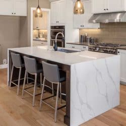Beautiful kitchen in new home with island, pendant lights, and hardwood floors, Does A Kitchen Island Need An Outlet?
