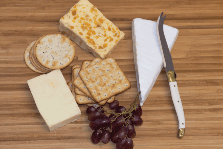 Cheese board with a variety of cheeses, crackers and red grapes. What Is The Hook On A Cheese Knife For