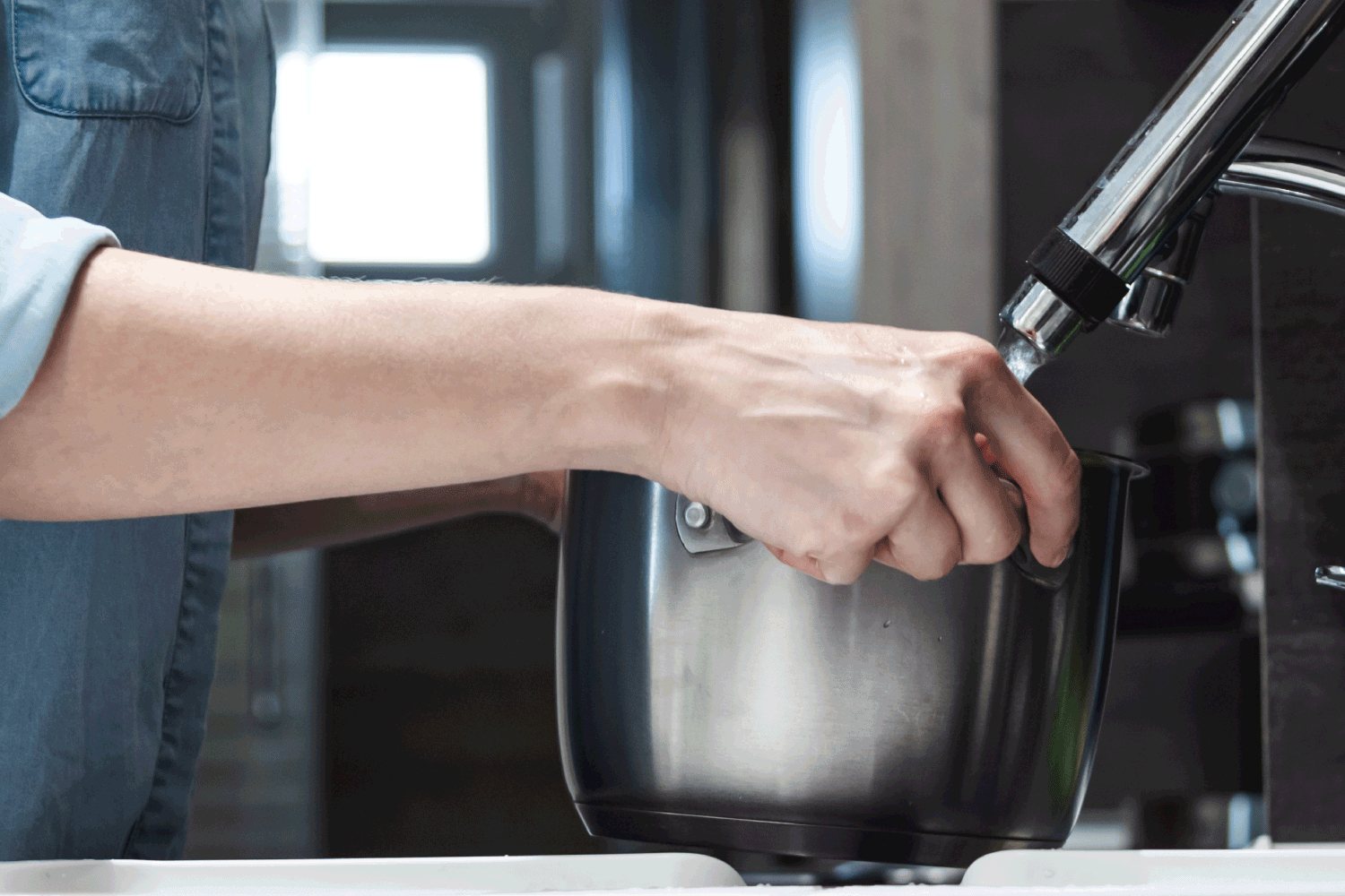Close up woman filling saucepan with tap water.