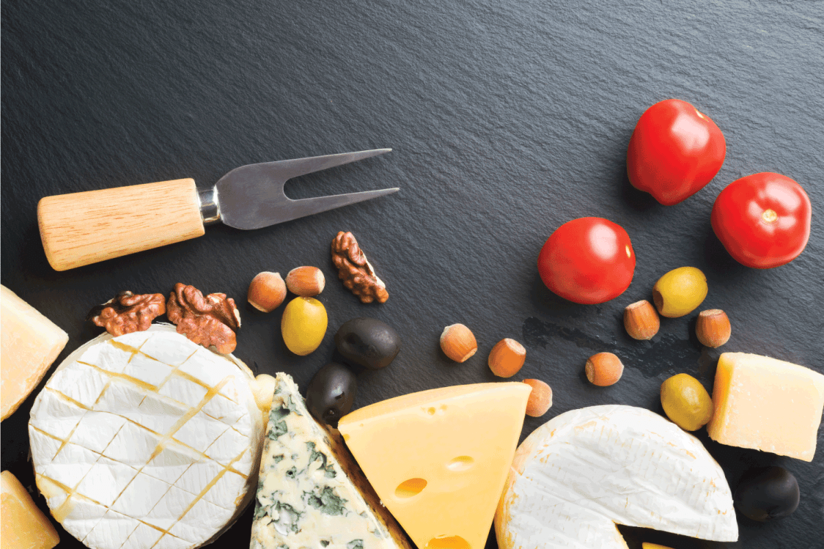 Different varieties of cheese, tomatoes and nuts with cheese fork