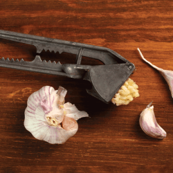 Garlic crushed and garlic press on a brown wooden table. 5 Garlic Press Alternatives To Try Our
