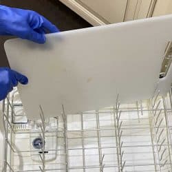 Loading dirty cutting board into an empty dishwasher while wearing rubber gloves, Is A Cutting Board Dishwasher Safe?