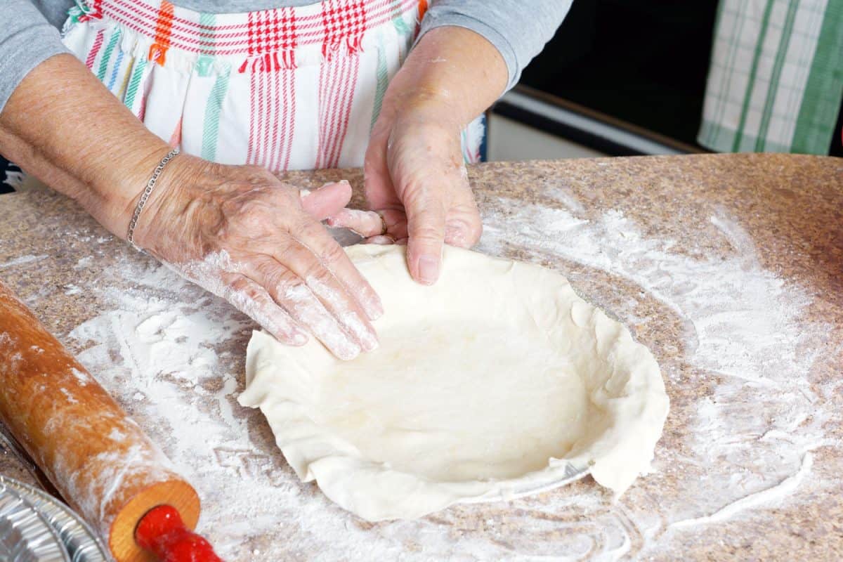 A woman preparing the pie crust on a pie mold