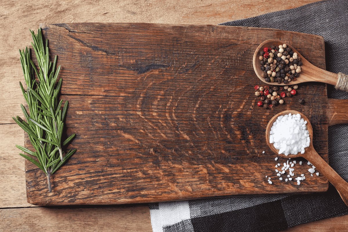 Salt, pepper and rosemary branch on top of wooden chopping board. Does A Cutting Board Need To Be Oiled