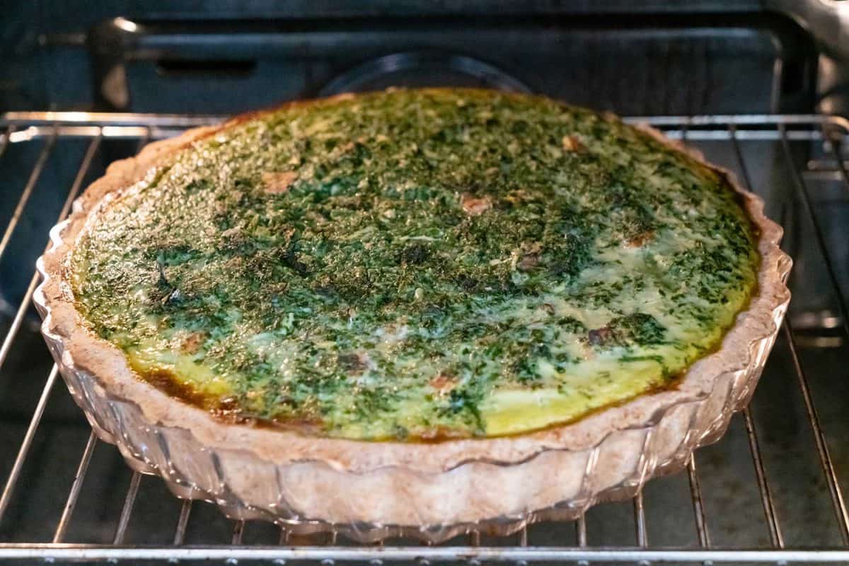 Spinach and tomato quiche baking inside oven