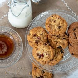 A glass bowl filled with chocolate chips and a jar of milk, How Long Do Chocolate Chip Cookies Last?