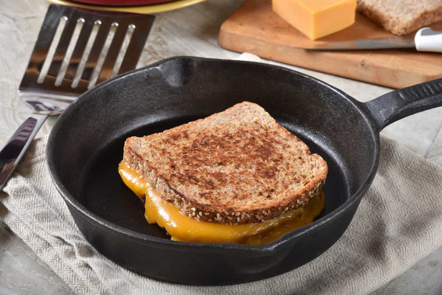 A grilled cheese sandwich on sprouted multi-grain bread in a cast iron skillet