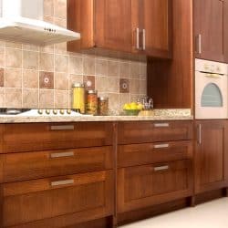 A kitchen with oak cabinetry brown tiled backsplash and a white rangehood, How To Adjust Kitchen Drawer Fronts