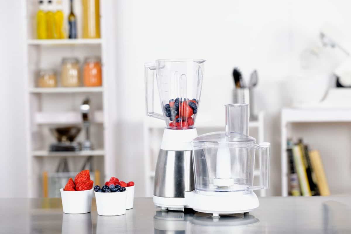A portrait of a blender on a kitchen worktop containing fruit and an empty food processor, How Long Does A Food Processor Last?