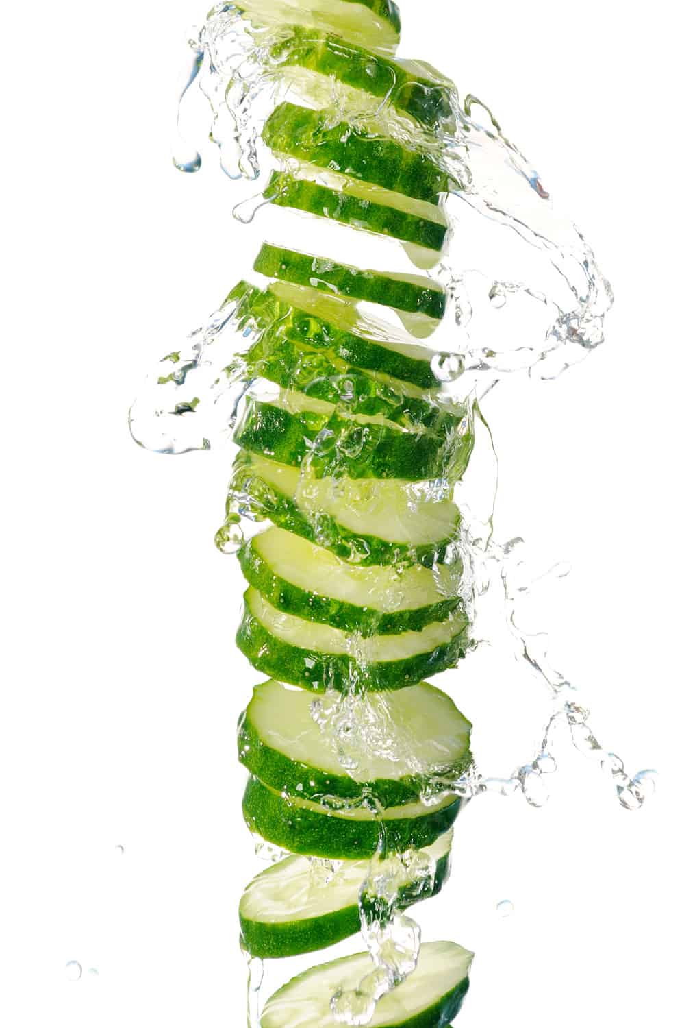 A slice of cucumber in the splash of water. Isolated on white