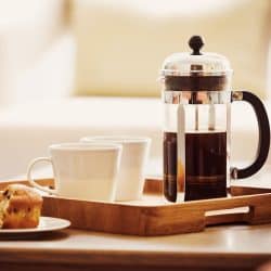 A small wooden tray with two white coffee cup s and a French press brewing coffee, Do French Presses Need Filters?