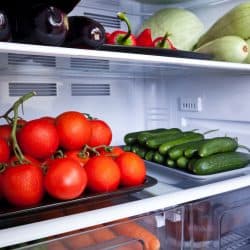 A tray full of tomatoes and cucumbers inside a fridge, Do Tomatoes Last Longer In The Fridge?