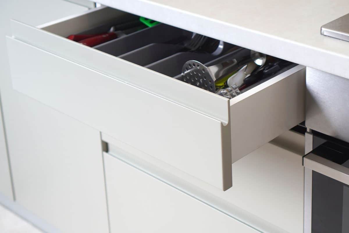 A white kitchen drawer with kitchen utensils inside