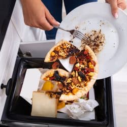 A woman throwing away burnt pizza into the trash compactor, Trash Compactor Not Working - What To Do?