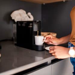 A woman getting a small cup of coffee on the coffee maker, Should A Coffee Machine Be Turned Off?