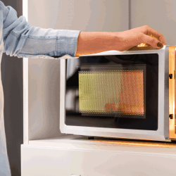 A woman's hands closing microwave oven door and preparing food in microwave. How To Clean Inside A Microwave [A Complete Guide]