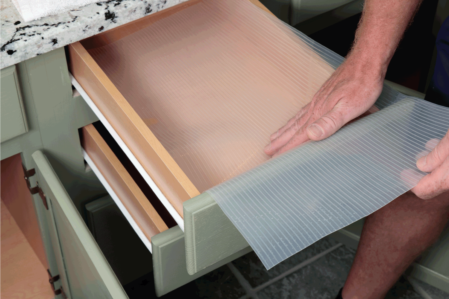 Caucasian Male Hands Placing Plastic Drawer Liner in a kitchen
