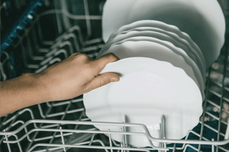 Closeup female hand holding a plate into the kitchen organizer. How To Organize Deep Kitchen Drawers [3 Practical Ideas]