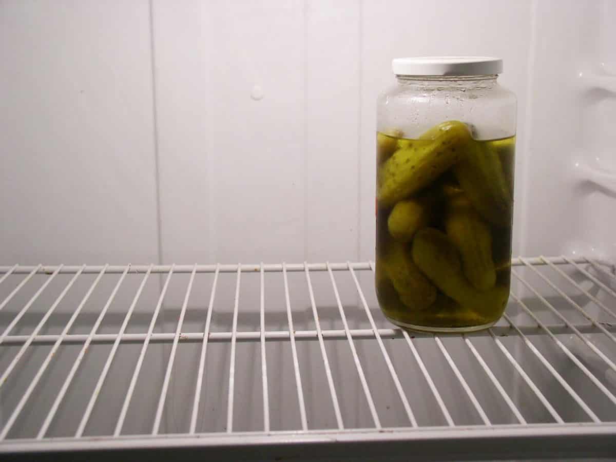 Close up of a pickle jar in an empty fridge
