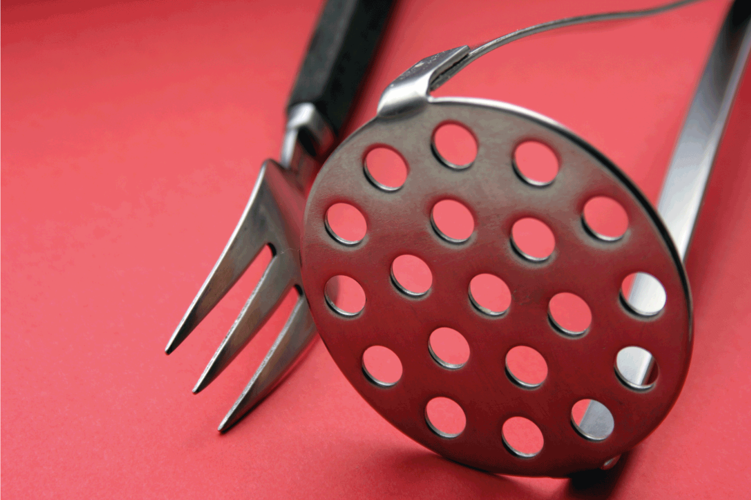 Fork and potato masher on red