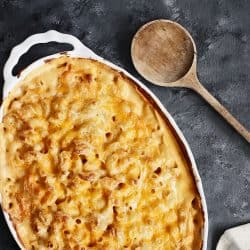 High angle view of a dish of fresh baked macaroni and cheese with table cloth and old wood spoon over a rustic dark background, Should You Cover Mac And Cheese When Baking?