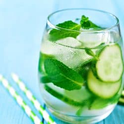 Homemade cucumber and mint lemonade in a glass on a blue wooden background, Should You Keep Cucumbers In The Fridge? [The Answer May Surprise You!]