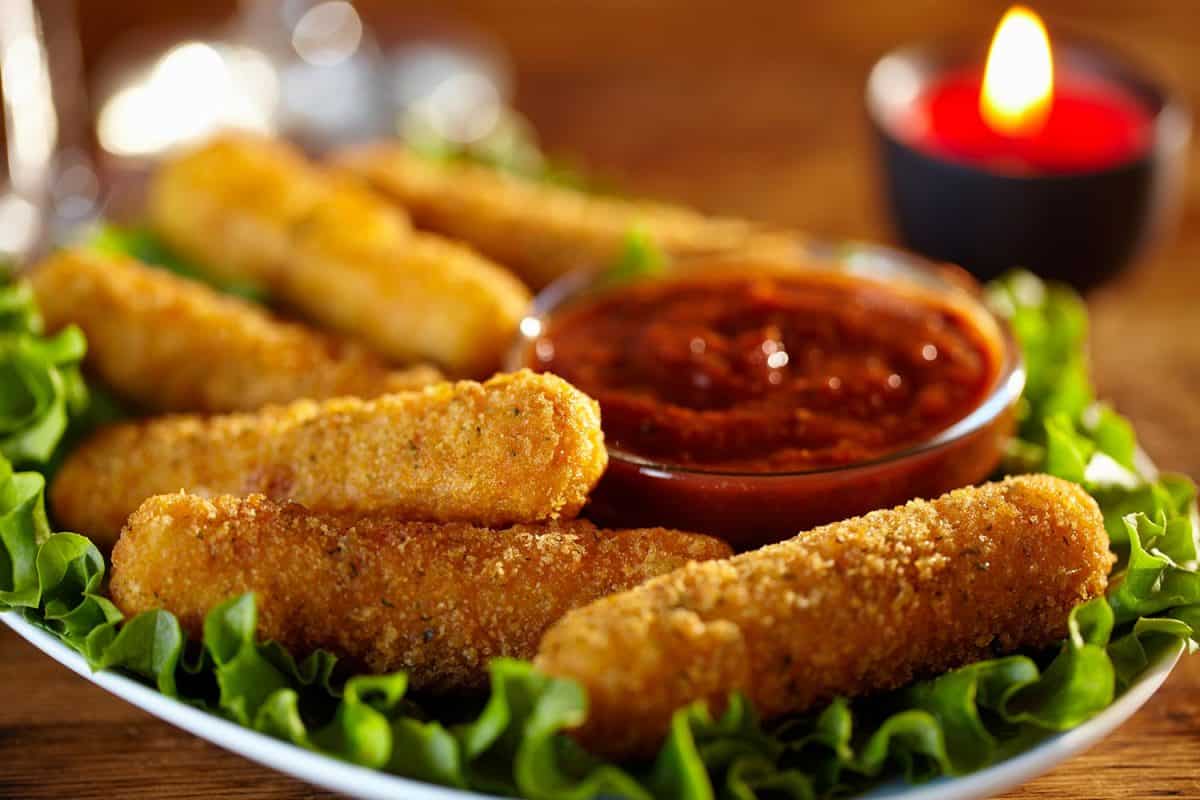 Mozzarella sticks with marinara dipping sauce on bed of lettuce