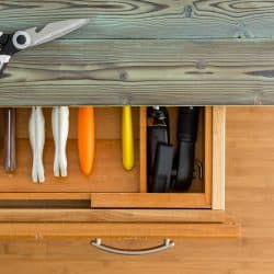 Neat line of colorful knives in a fitted drawer in a wooden kitchen cabinet with rustic counter top viewed from overhead with a pair of scissors or shears on top, Should You Paint The Inside Of Kitchen Drawers?