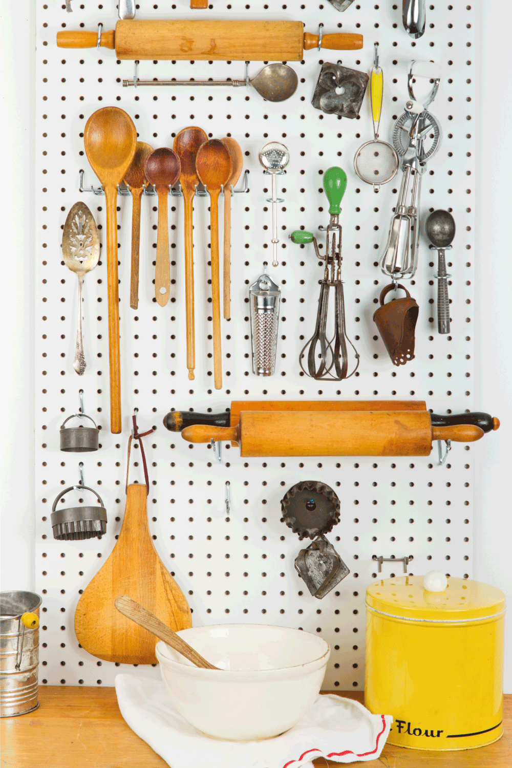 Pegboard Filled with Old Cooking Gadgets In front of a counter with baking supplies