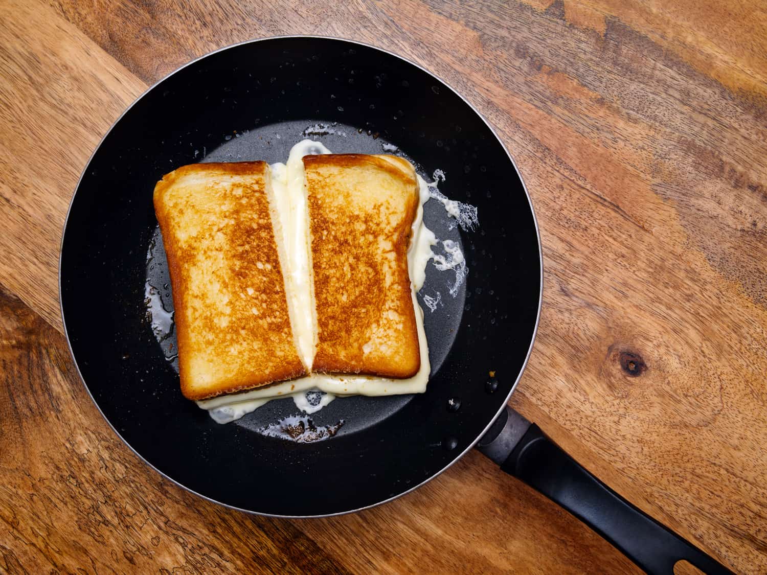 Photo of a grilled cheese sandwich cooking in a large frying pan.