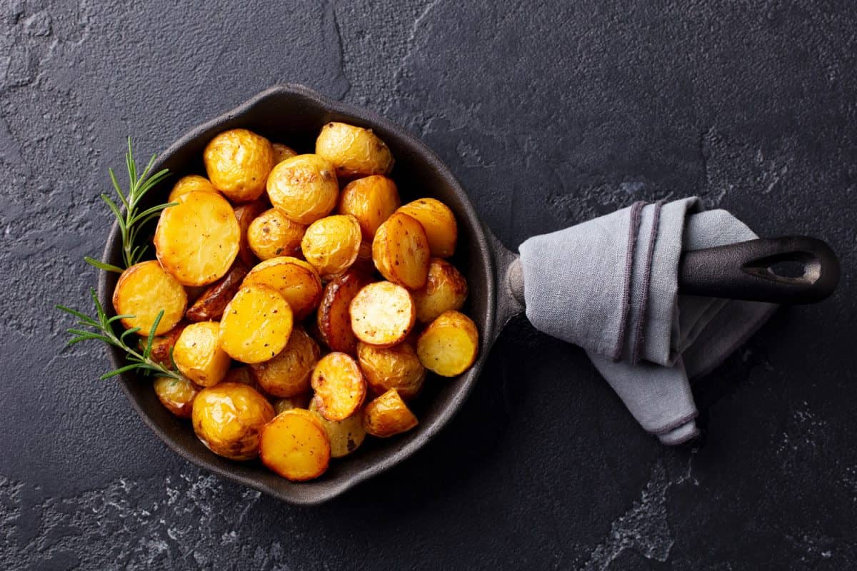 Roasted baby potatoes in iron skillet. Dark grey background, Should You Boil Potatoes Before Roasting Them?