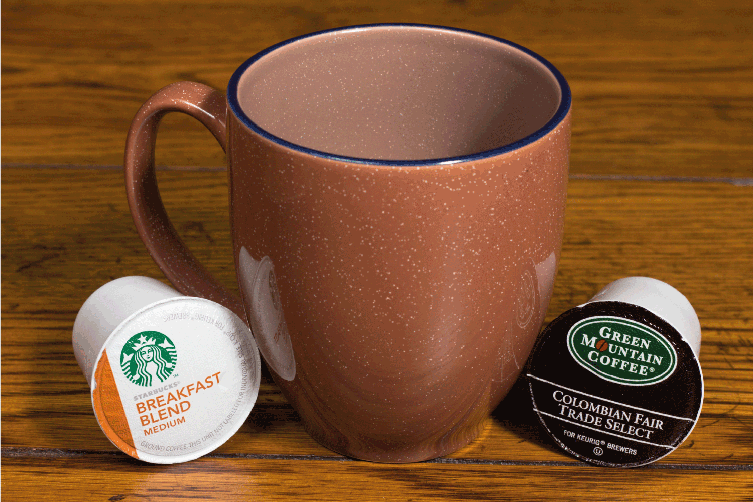 Single serving, coffee k-cups, also known as pods for Keurig coffee makers beside a coffee cup