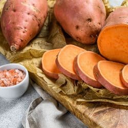 Sliced potatoes and a small dip on the side placed on top of a wooden chopping board, Should You Soak Sweet Potatoes Before Baking?