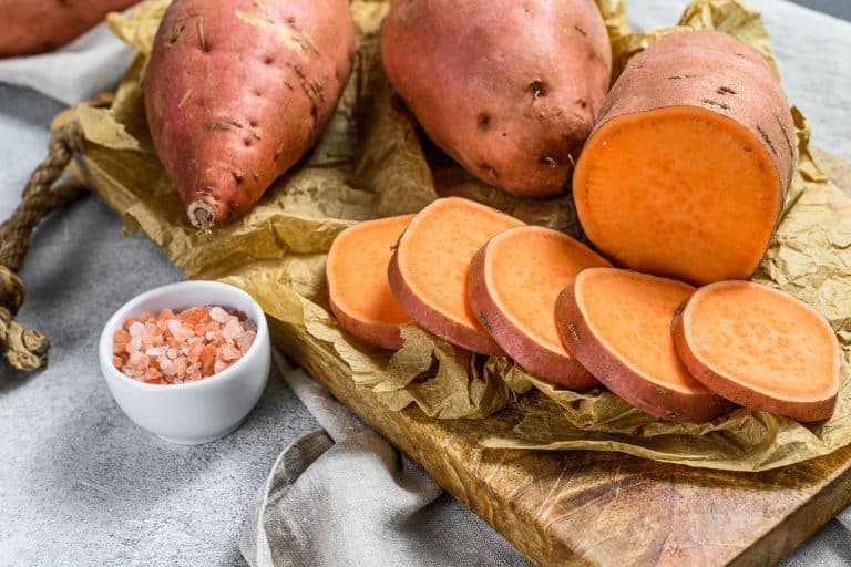 Sliced potatoes and a small dip on the side placed on top of a wooden chopping board, Should You Soak Sweet Potatoes Before Baking?