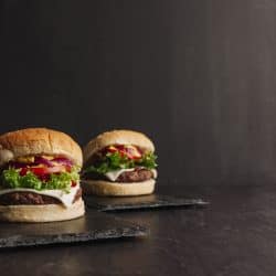Two tasty beef burger with lettuce, tomatoes, cheese, and bacon on a small black tray, Types Of Hamburger [Everything You Ever Need To Know]